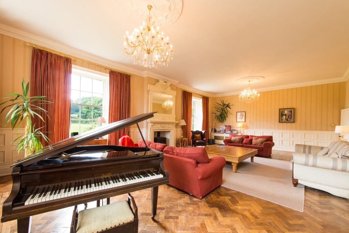Stunning light filled lounge with a baby grand piano and views east to the sea and south to the golf course, wood burner, baby grand piano, 3 large sofa's, games, books and toys